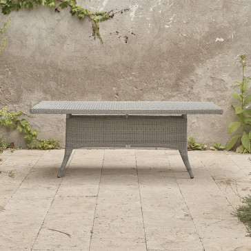 Eight seater grey rattan garden table in front of stone wall