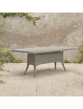 Eight seater grey rattan garden table at an angle in front of stone wall