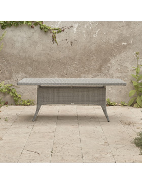 Eight seater Grey rattan garden table. On a terrace in front of stone wall