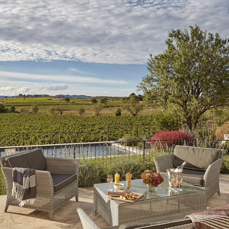 Rattan garden furniture in French grey two-seater couch matching armchairs and coffee table overlooking a Southern French Garden