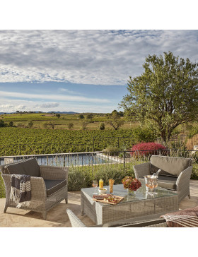 Rattan garden furniture in French grey two-seater couch matching armchairs and coffee table overlooking a Southern French Garden