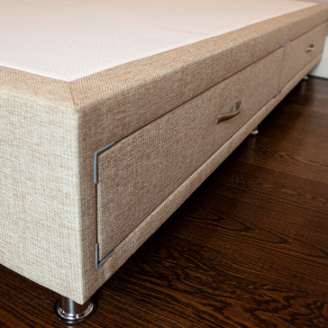 Divan bed base with drawers upholstered in an oatmeal furniture fabric pictured on a wooden floor